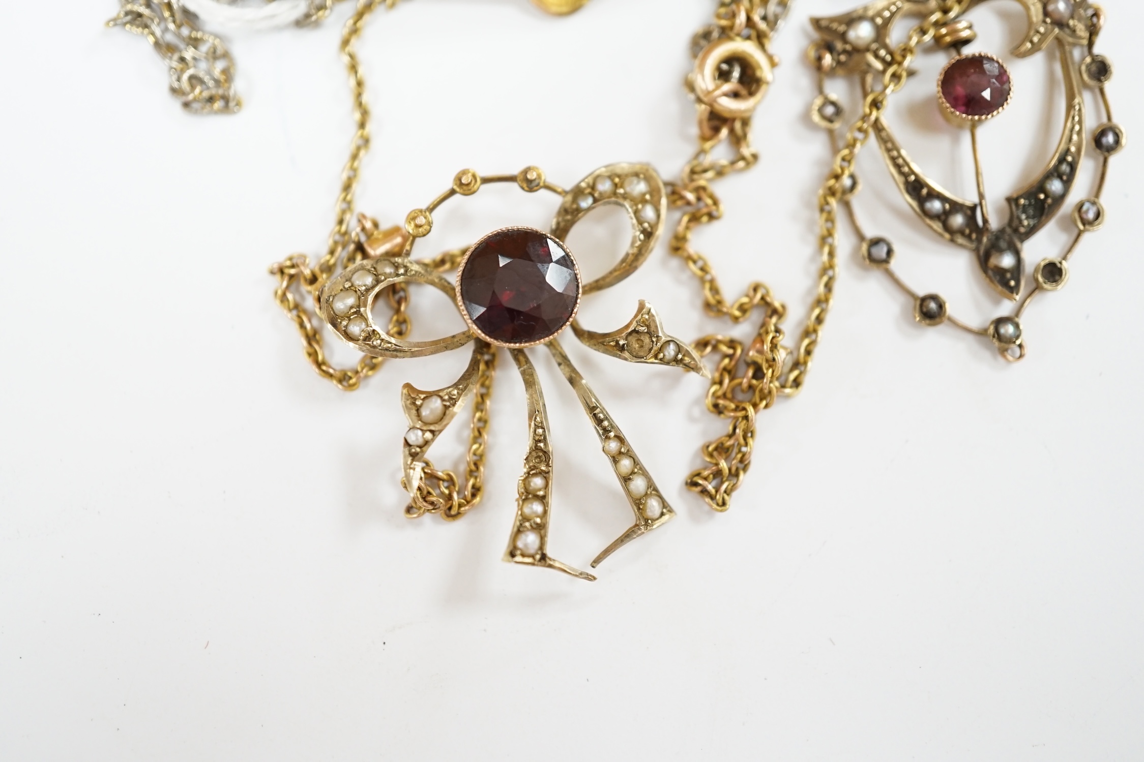 An early 20th century 9ct, garnet and seed pearl set pendant necklace, 43cm, one other similar 9ct and gem set pendant, on a gilt metal chain and a yellow 'metal 'mother' brooch. Condition - fair